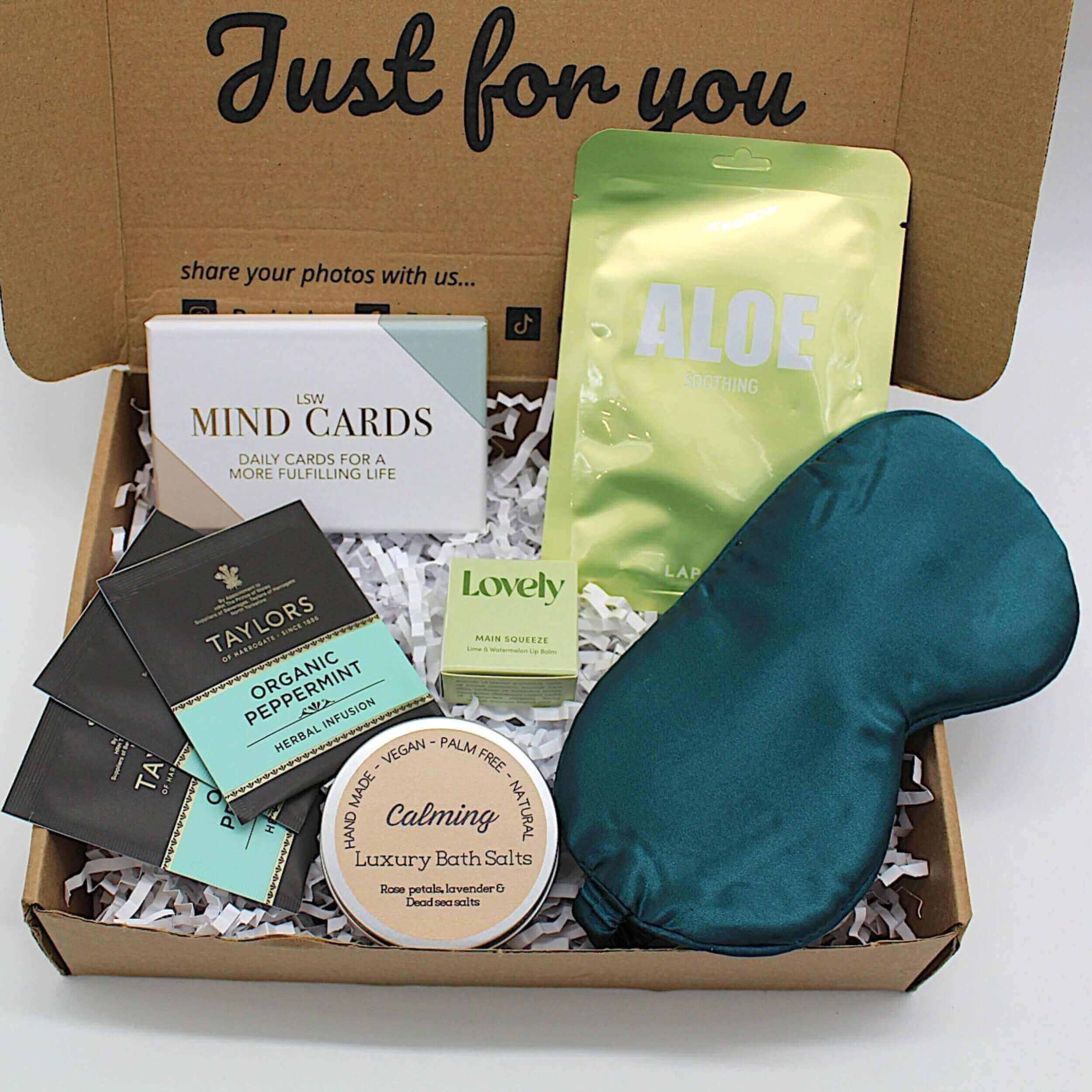 Gifts for mental health wellness in a self-care box with bath salts, tea, and relaxation items.
