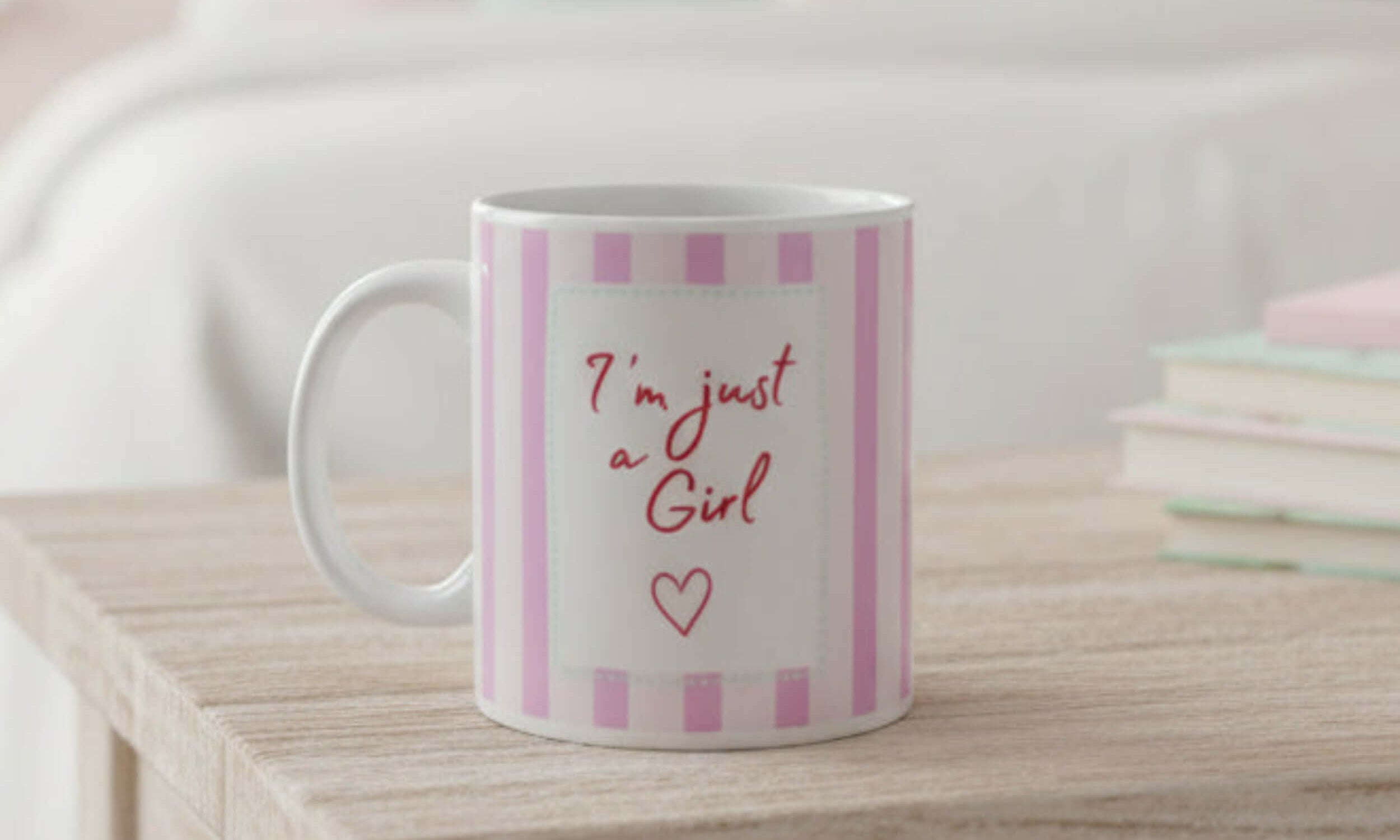 Am just a girl mug on a wooden table with pink stripes and an empowering quote.
