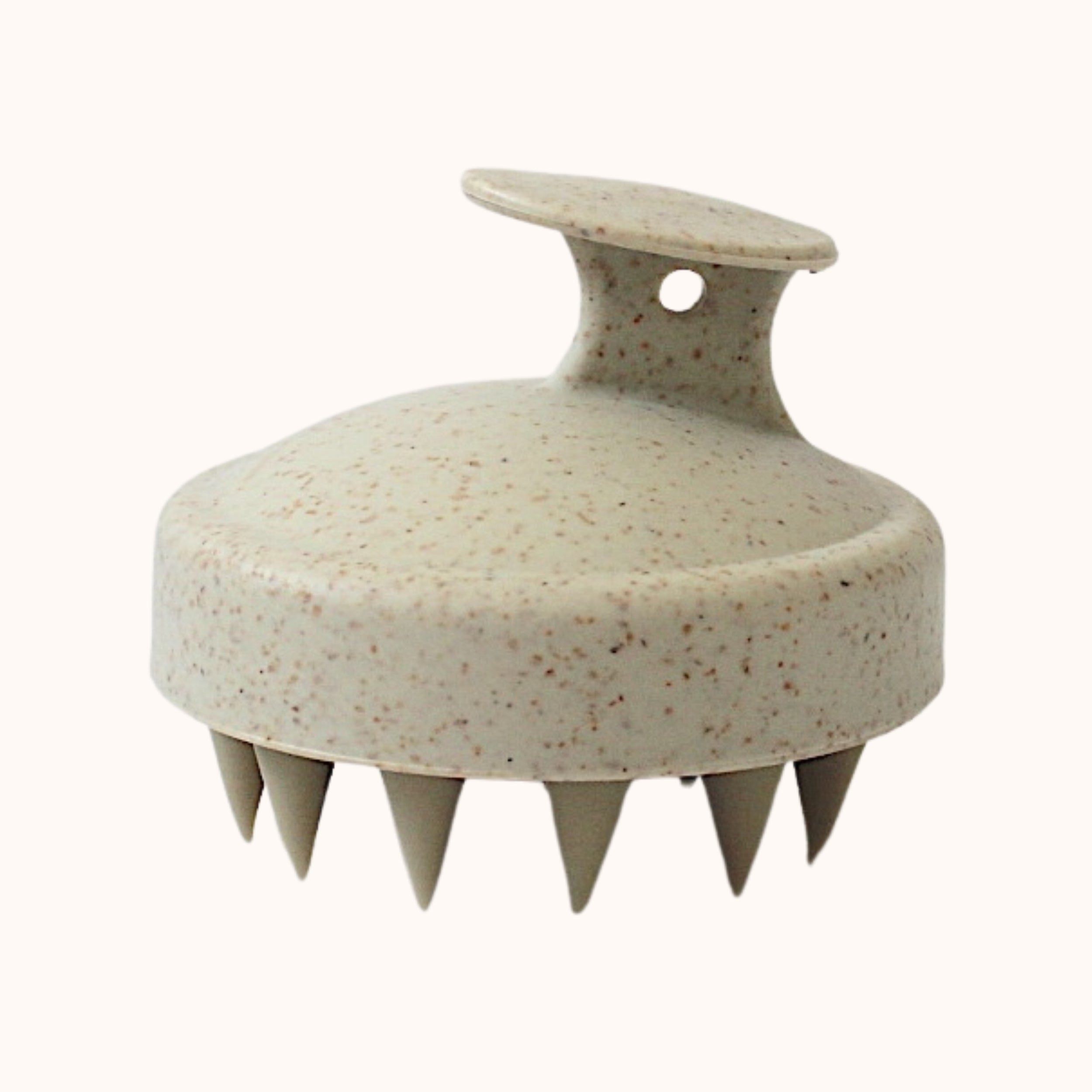 A round spa-style scalp massager with a textured, speckled beige and brown surface, featuring a top handle and multiple short, pointed silicone spikes on the bottom, shown against a plain off-white background.