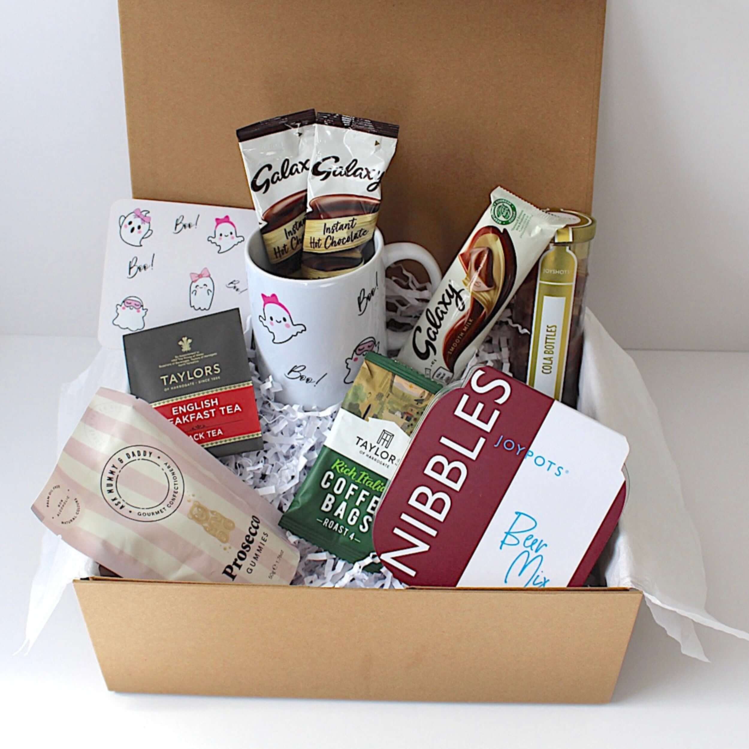 Cute Boo! gift box includes cute ghost mug, matching coaster, prosecco gummies, tea bag, 2 hot chocolate sachets, coffee bag, galaxy chocolate bar, beer mix nibbles and cola bottles.   