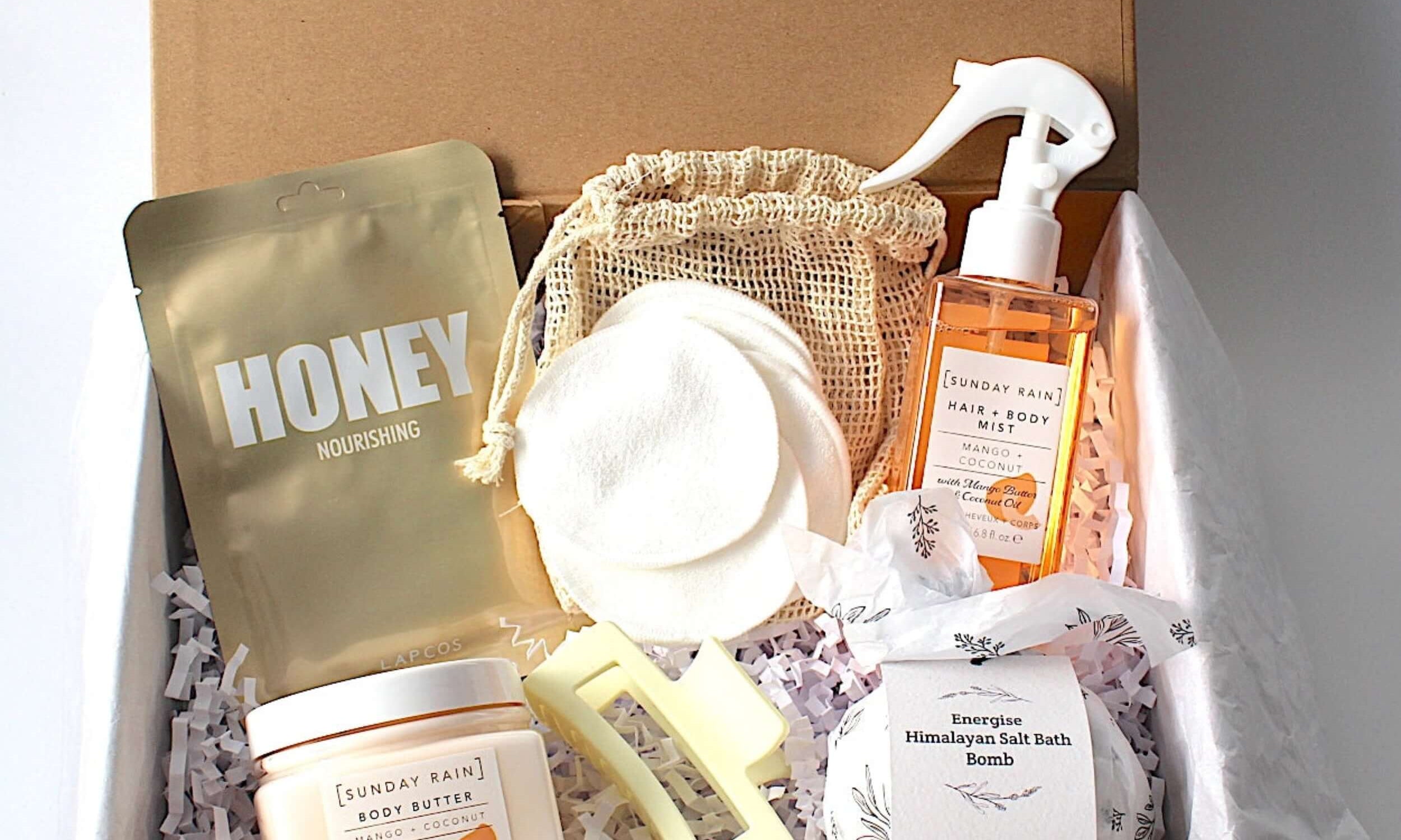 Luxury self-care gift box for ultimate relaxation and pampering. Includes a magnetic keepsake box, hydrating honey sheet mask, Sunday Rain mango & coconut hair and body mist spray, nourishing mango & coconut body butter, Energise Himalayan bath bomb, reusable face cloths in a bamboo bag, and a stylish claw hair clip. Perfect for birthdays, self-care gifts, and spa gift sets.
