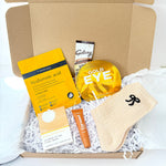 Golden Christmas pamper gift box with hyaluronic acid face mask, gold eye patches, citrus bath bar, caramel lip balm, cream bow socks and hot chocolate