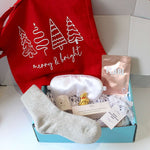 Festive merry and bright ift box, blue gift box with white satin sleep mask, pearl sheet mask, dotted star tea light holder, 3 aromatherapy soy wax tea llights, cashmere grey socks, sensual bath bomb, and Lindt reindeer. .    