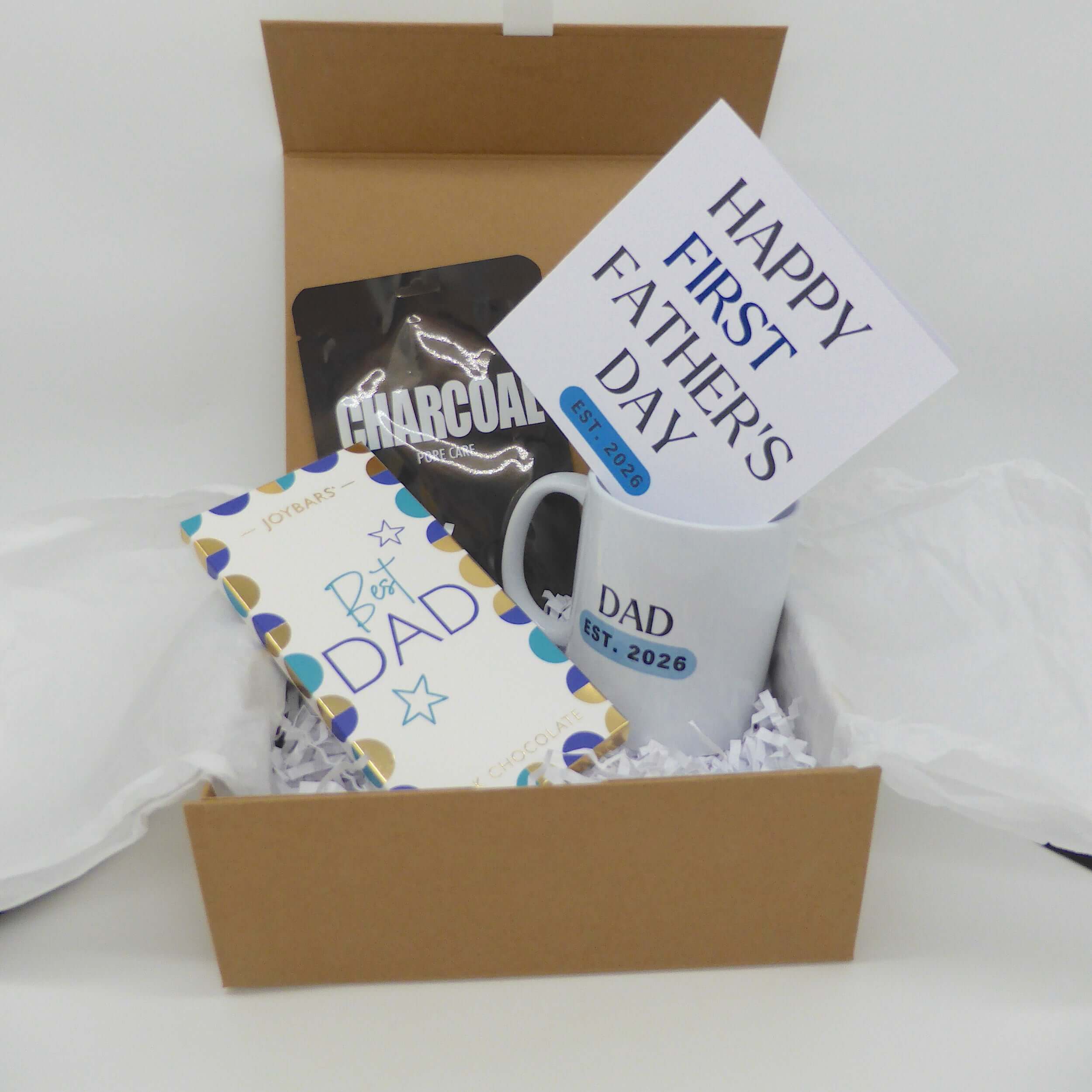 Father's Day gift for new dad in a gift box with mug, card, chocolate, and charcoal mask.
