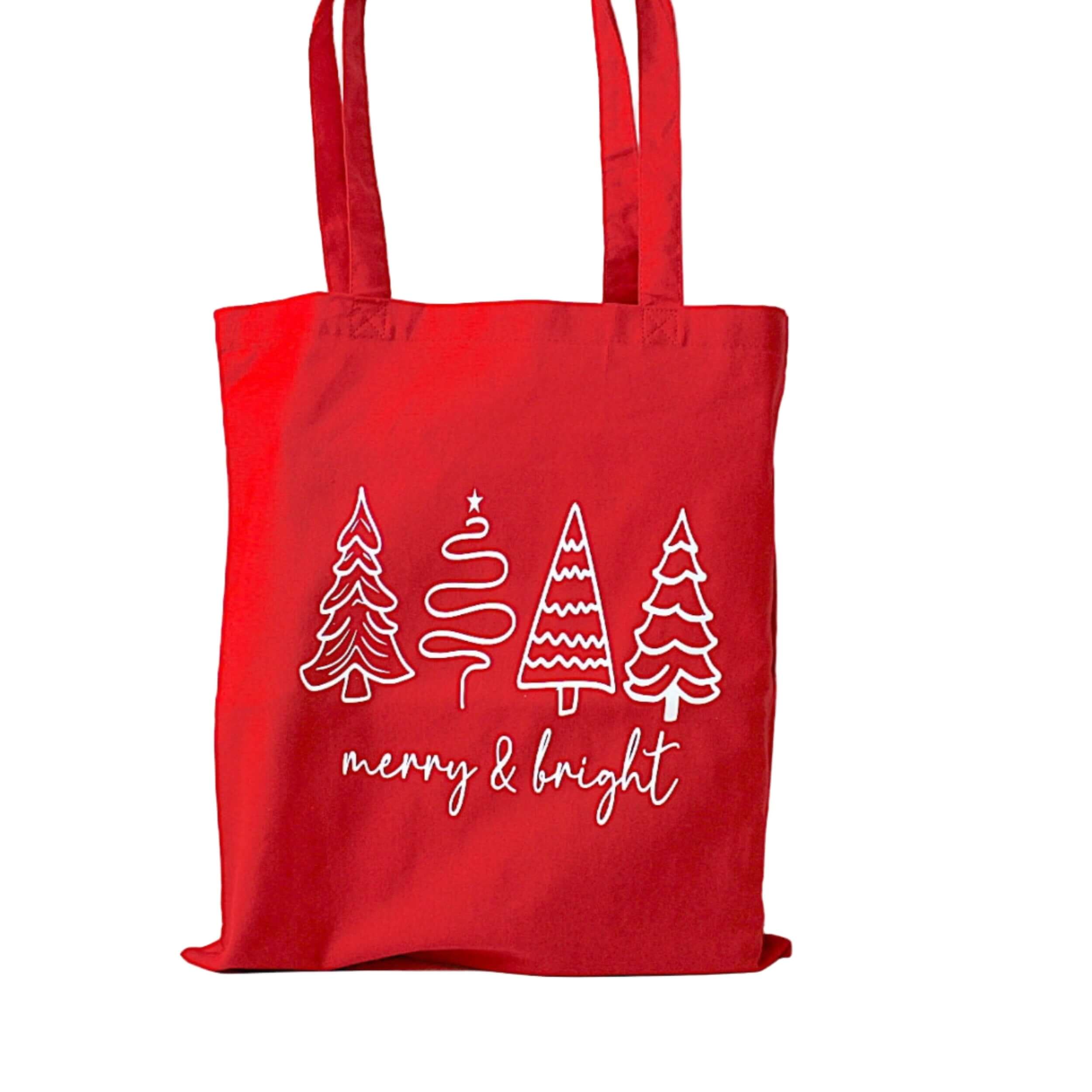 Red tote bag with Christmas tree designs and 'merry & bright' text on a white background