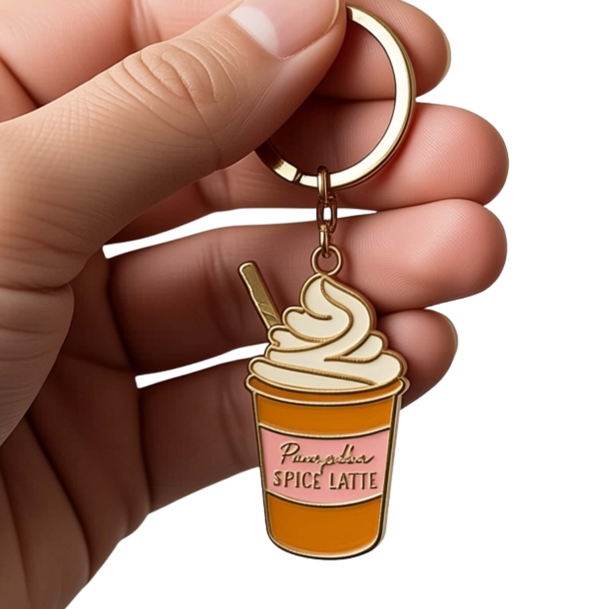 A hand holding a gold-tone metal keychain charm shaped like a cup of spice latte with whipped cream and a straw. The charm has a pink label reading 'Pure Bar Spice Latte' and is shown against a plain white background.