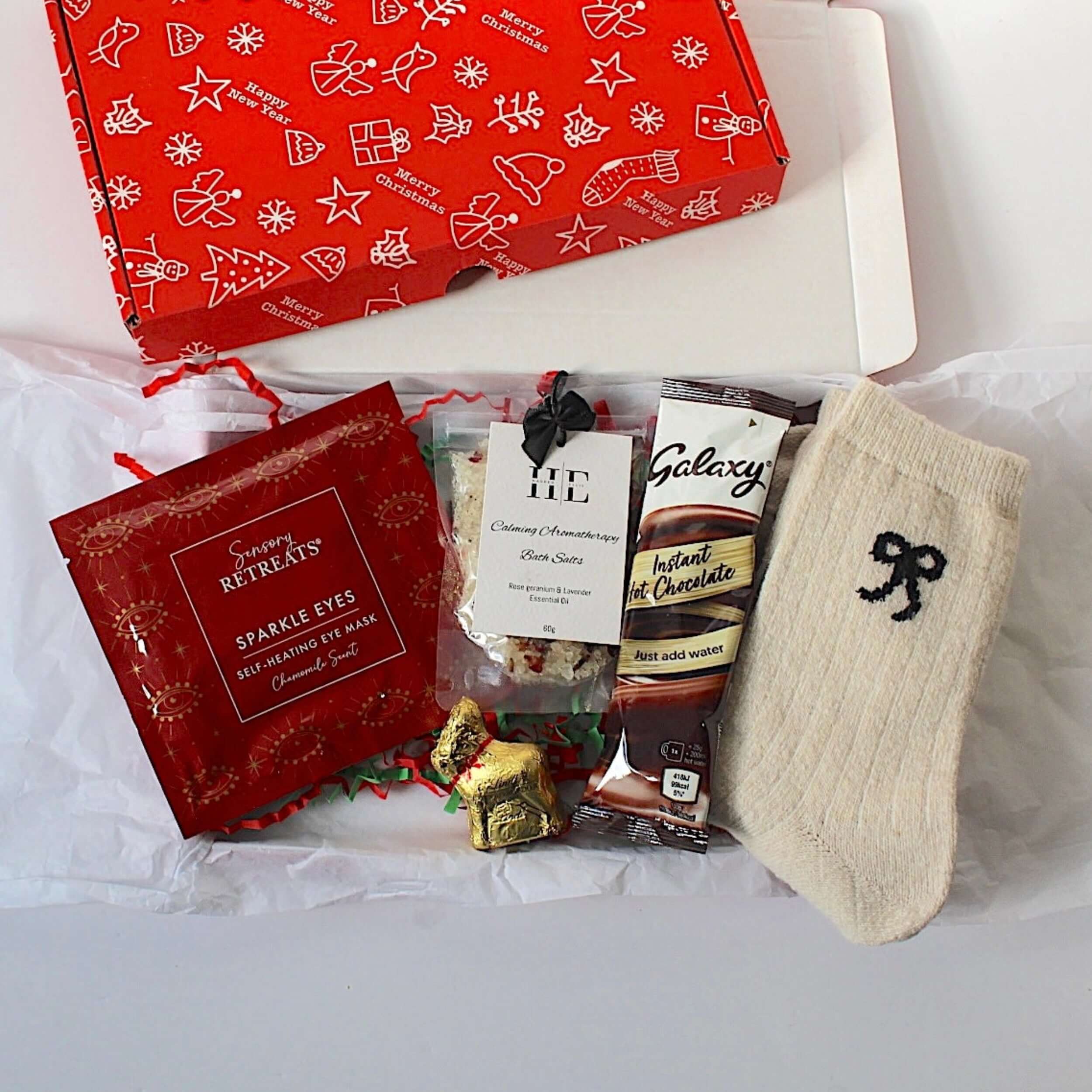 Letterbox festive gift for her, sensory retreats sparkle eyes self heated eye mask, wool socks, calming aromatherapy bath salts, lindt reindeer and galaxy hot chocolate.    