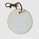 Round keychain with 'there is beauty in every moment' 