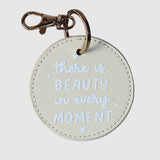 Round keychain with 'there is beauty in every moment' 