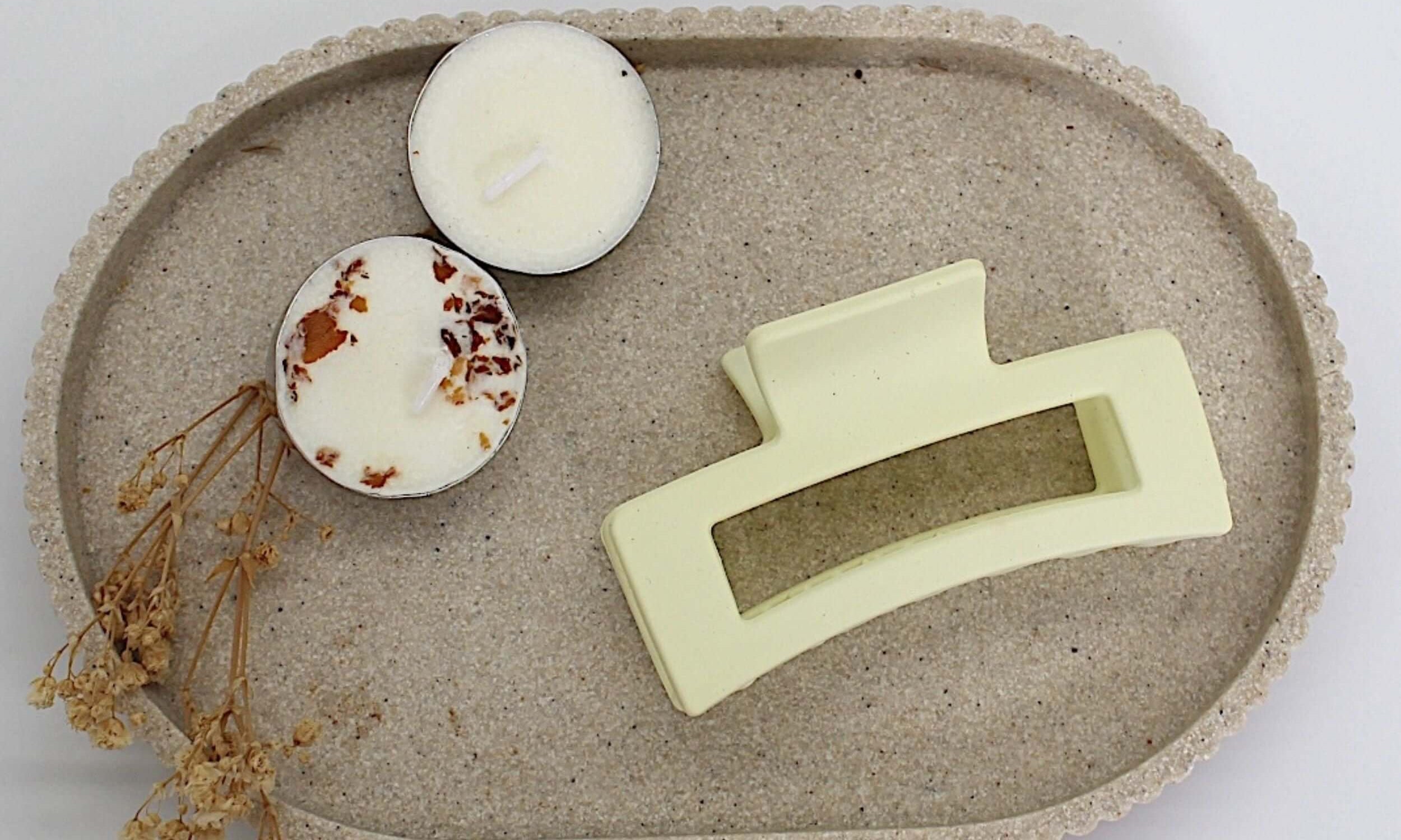 Beige bar claw clip placed on a decorative tray with candles and dried flowers.
