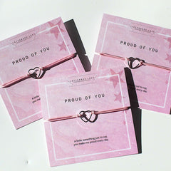 Three Proud of You celebration bracelets displayed on pink cards with heartfelt messages.